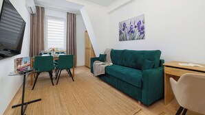 Un soggiorno moderno con un divano verde, un tavolo da pranzo e una televisione.