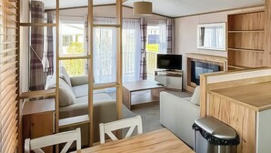 A compact living space with a sofa, a dining table, a TV, and a kitchen area.