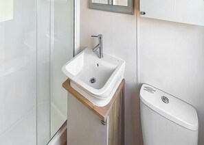 Un baño con un lavamanos blanco, un espejo y un inodoro.