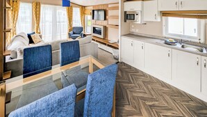 A modern interior with a dining area, sofa, TV, kitchen, and wooden flooring.