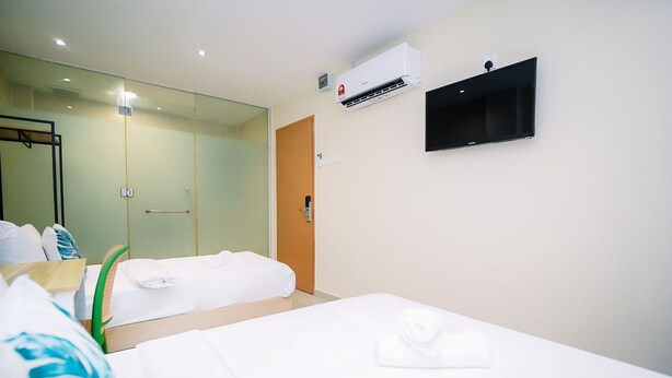 Habitación de hotel con cama, mesita de noche, espejo, armario, aire acondicionado y televisor.