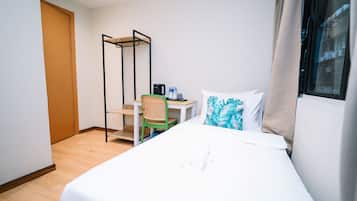 Une chambre d’hôtel comprenant un lit, un bureau avec une chaise, un distributeur d’eau et une fenêtre avec des rideaux.