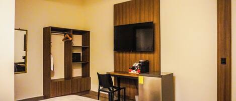 A hotel room with a bed, a desk with a chair, a television, and a wardrobe.