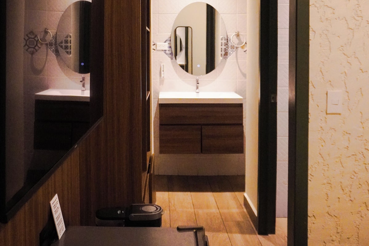 Une salle de bain moderne avec un meuble-lavabo en bois, un grand miroir et un espace lavabo séparé.