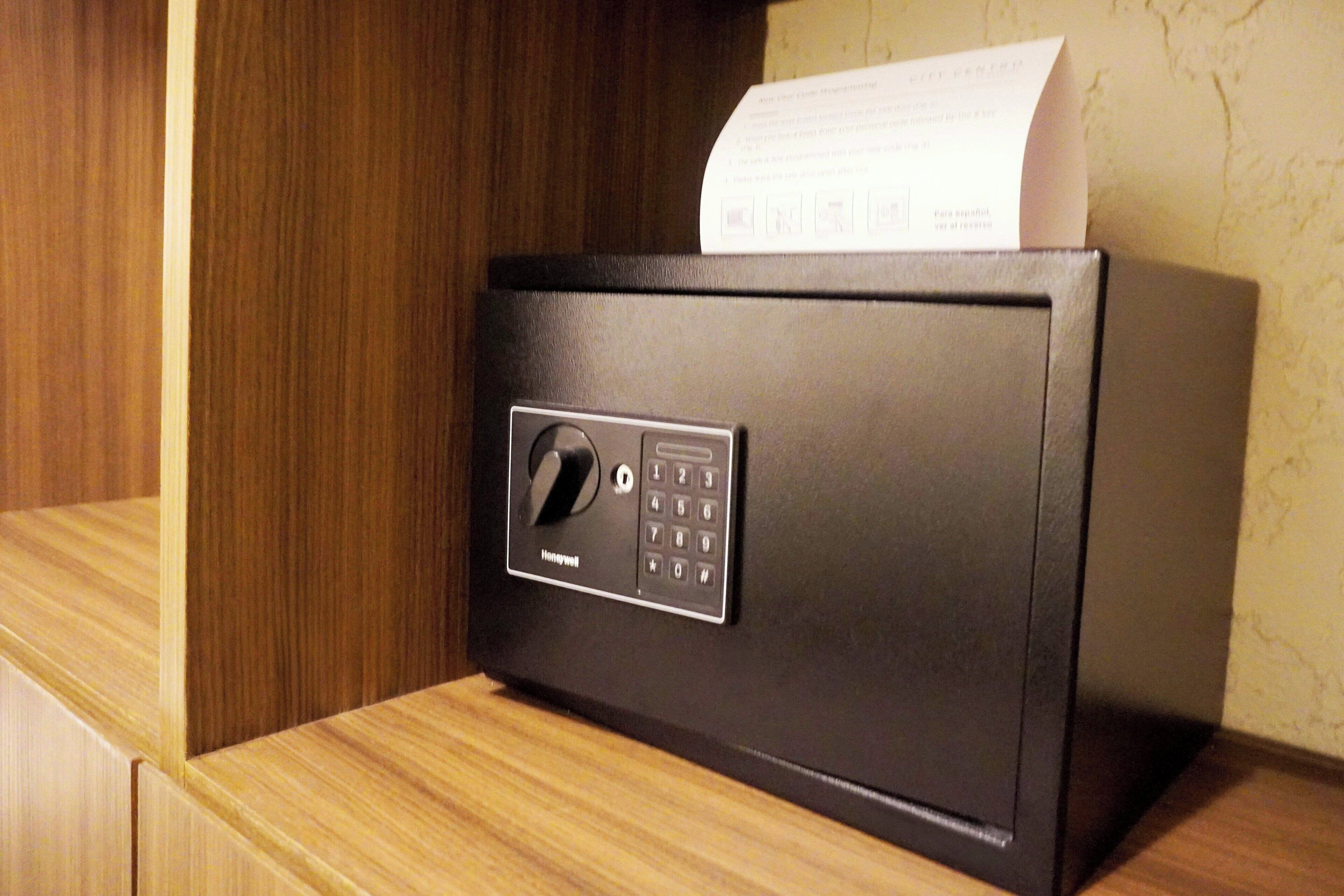 A black safe with a numeric keypad and a keyhole, placed on a wooden surface.