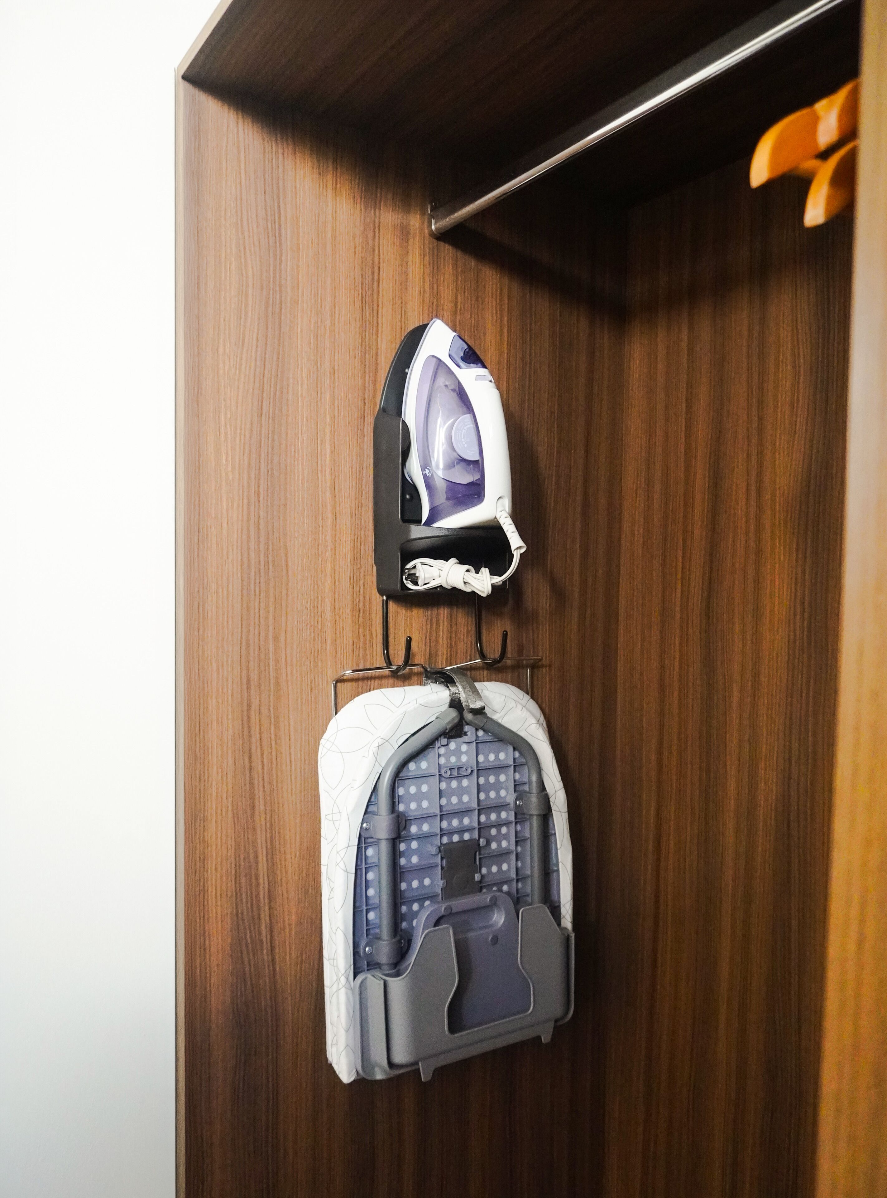 Een houten kast met een strijkijzer en een kinderwagen.