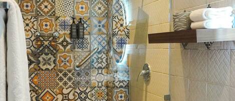 Un baño con pared de ducha enlosada, inodoro y piso de madera.