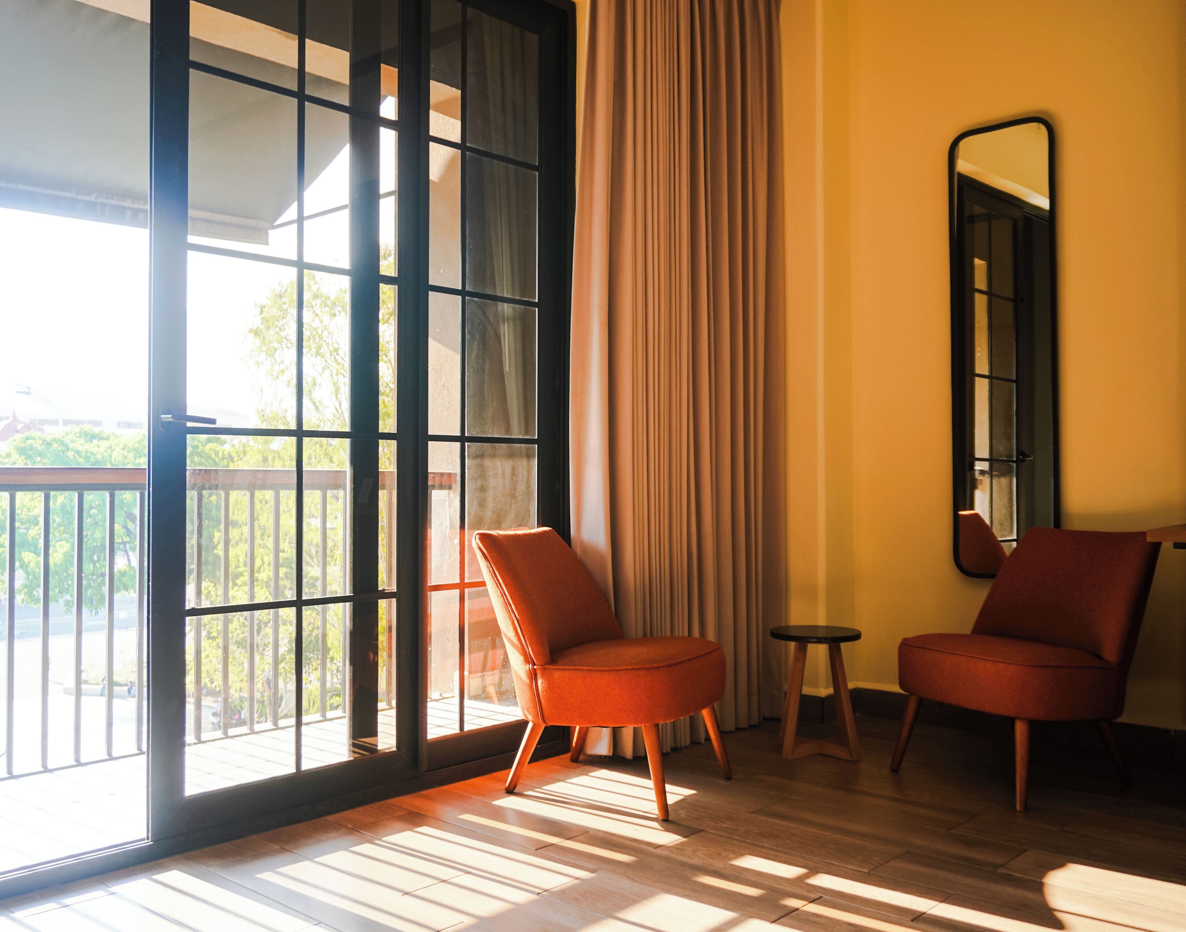 A room with a large sliding glass door, two chairs, a small round table, and a mirror on the wall.