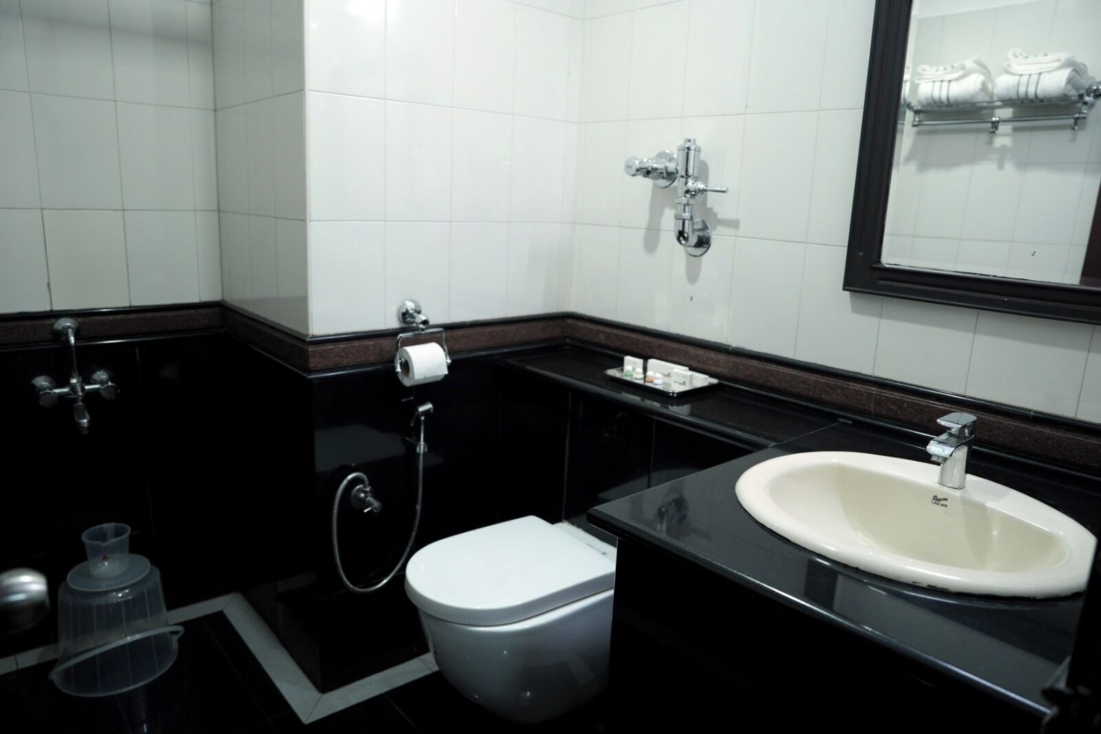 Un baño moderno con un lavamanos negro, inodoro blanco y un espejo sobre el lavamanos.