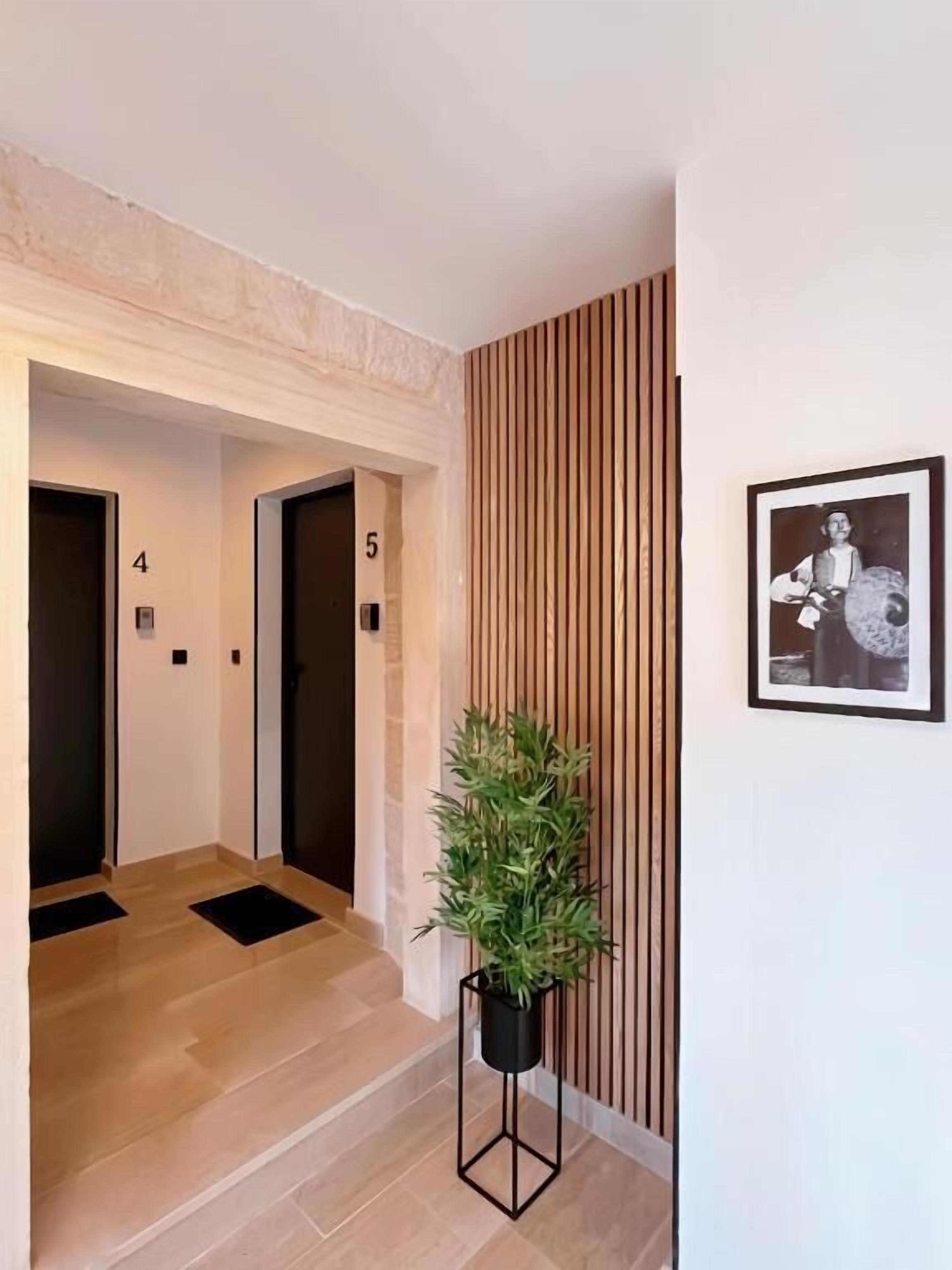 A hallway with doors numbered 4 and 5, a potted plant, and a framed picture on the wall.