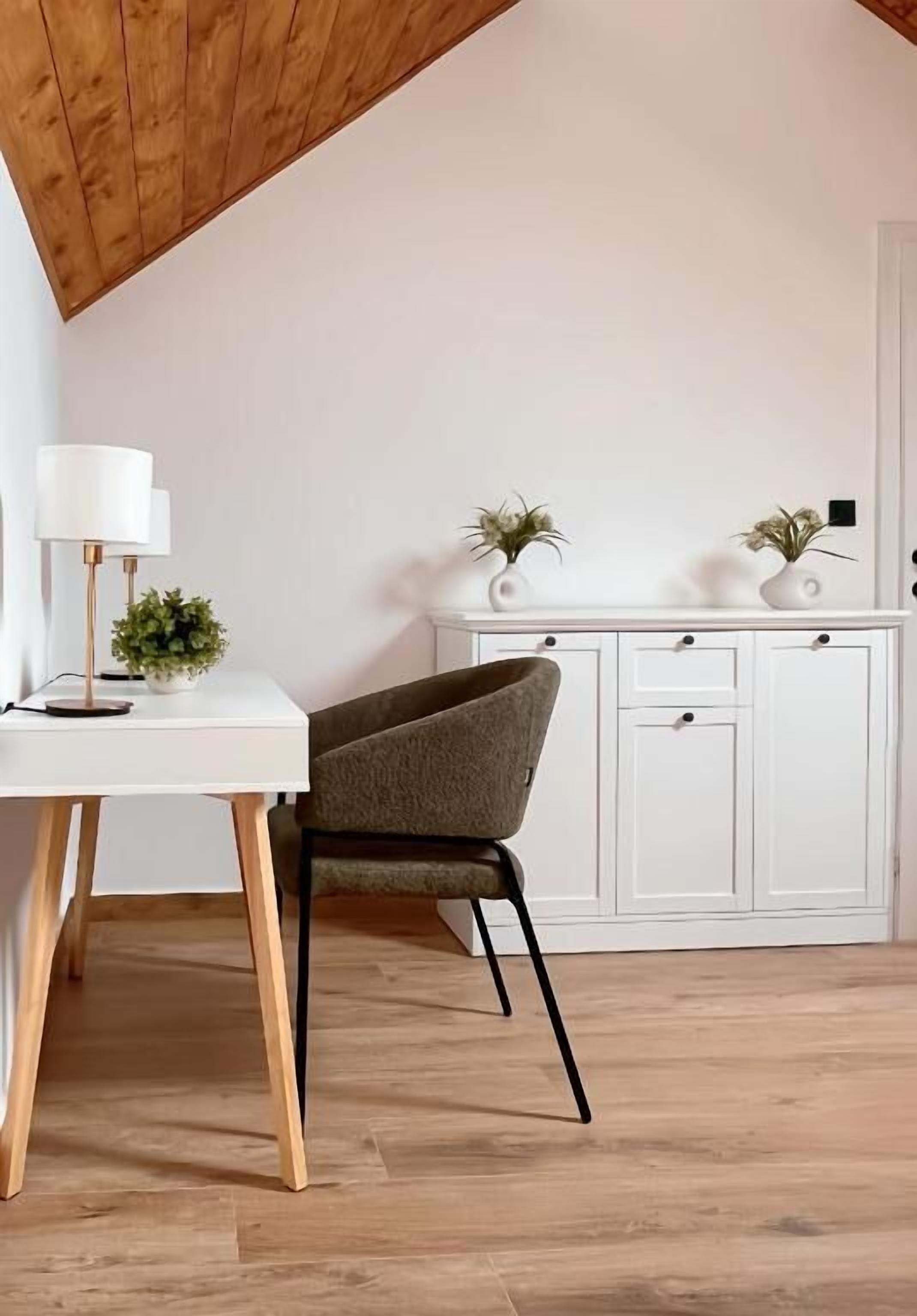 A modern room with a white desk, a green chair, a white cabinet, and two potted plants.