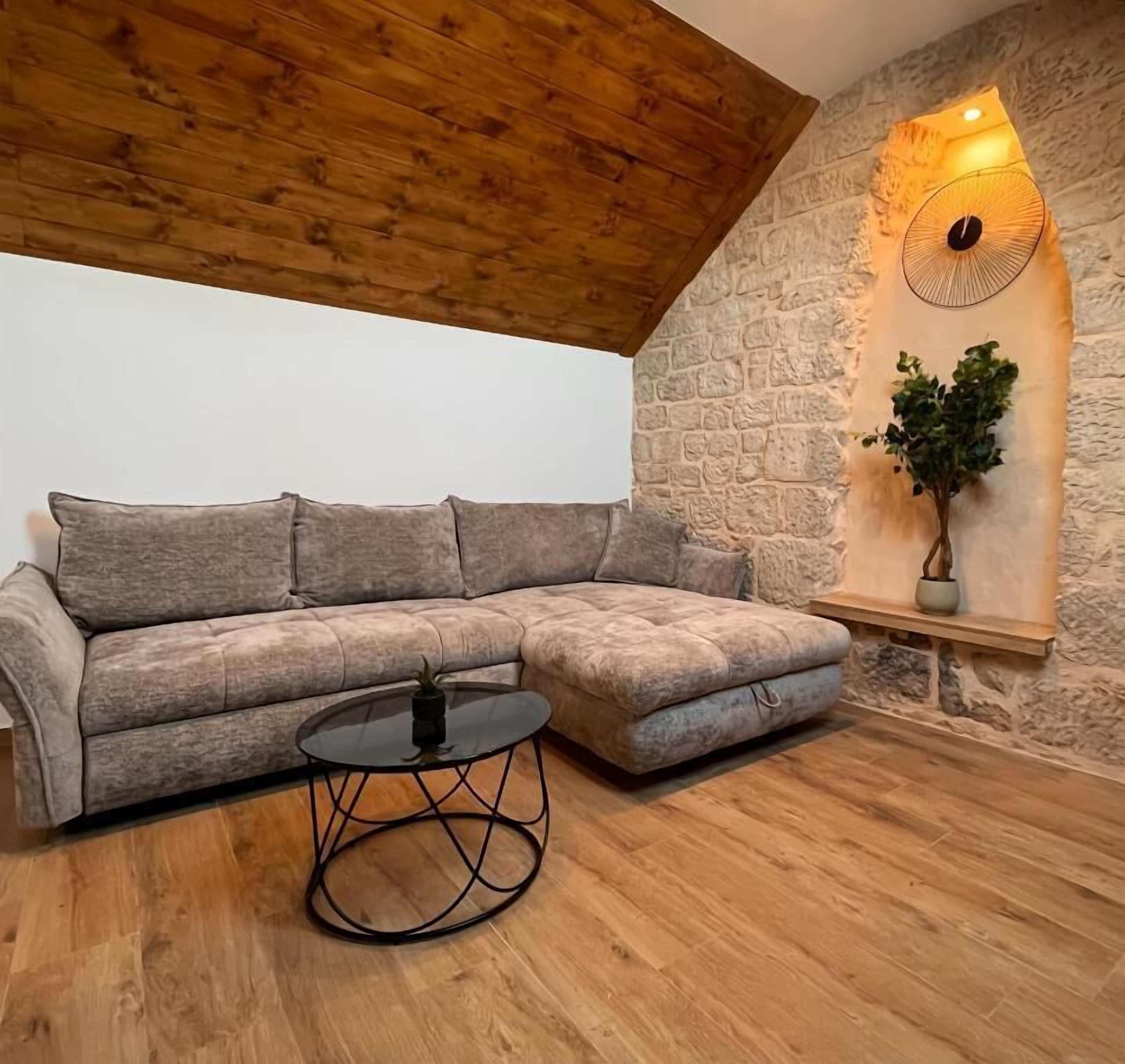 A cozy living room with a wooden ceiling, a stone wall, and a modern sectional sofa.