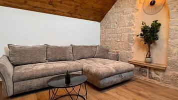 A cozy living room with a wooden ceiling, a stone wall, and a modern sectional sofa.