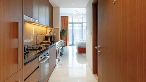 A modern kitchen with stainless steel appliances, a dining area with a table and chairs, and a bedroom with a bed and window. - Luxury Studio with Pool and Parking (Dubai)
