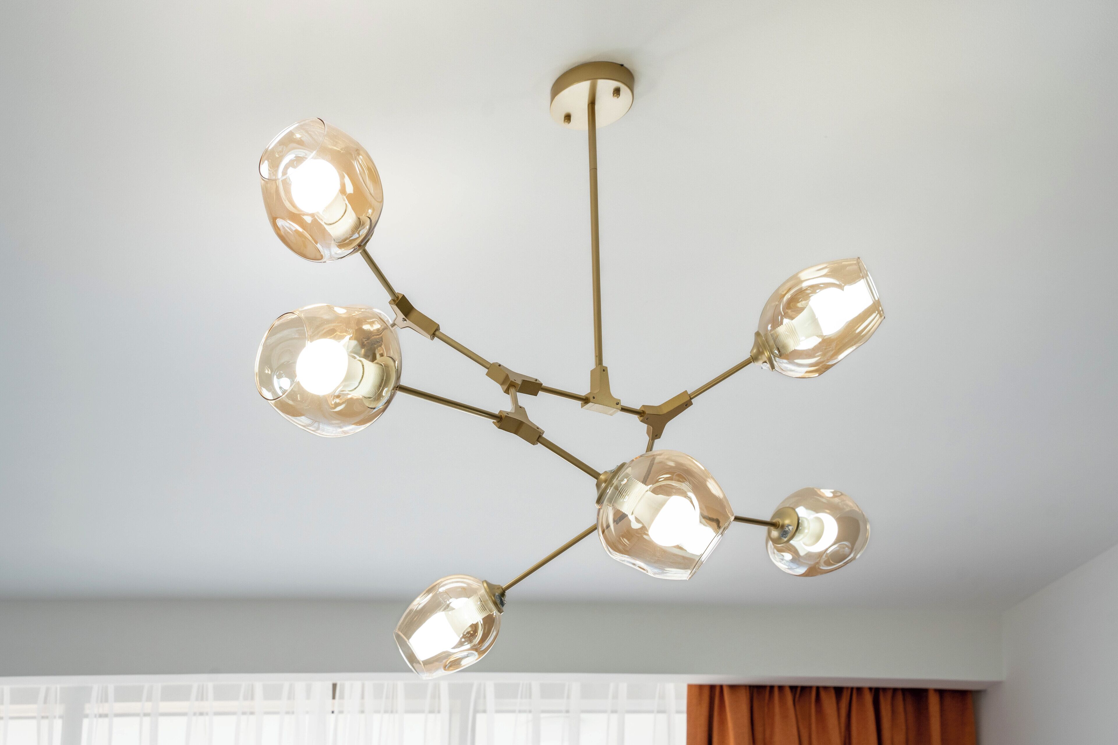 A ceiling with a modern chandelier with multiple glass shades and a central light fixture.