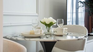 A dining table set with white plates, glasses, and a vase of white flowers. - Luxury Studio with Pool and Parking (Dubai)