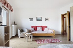 Une chambre à coucher comprenant un lit, un canapé, une petite table, un radiateur et trois tableaux encadrés accrochés au mur.