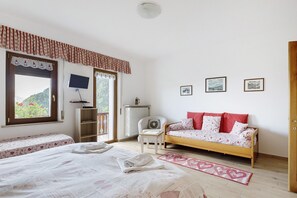 Une chambre avec un lit, un canapé, une télévision et une fenêtre donnant sur un paysage verdoyant.