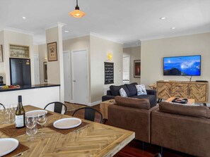 Un salon moderne avec un canapé, un téléviseur et un coin repas avec une table mise pour deux personnes.
