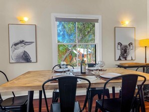 Un coin repas avec une table en bois, des chaises noires et des photos d’animaux sauvages encadrées accrochées aux murs.