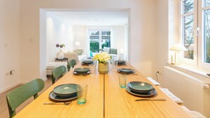 A dining room with a wooden table set for six, chairs, and a vase of flowers. - Vacation home "Nordwärts" in Tönning - garden, fireplace & space for 6 guests (Tönning)