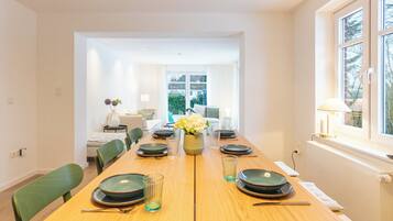 Ein Esszimmer mit einem Holztisch, gedeckt für sechs Personen, Stühlen und einer Blumenvase.