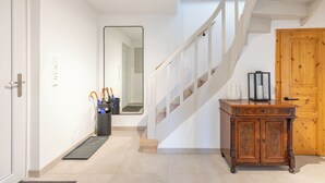 A hallway with a wooden cabinet, a mirror, and a staircase. - Vacation home "Nordwärts" in Tönning - garden, fireplace & space for 6 guests (Tönning)