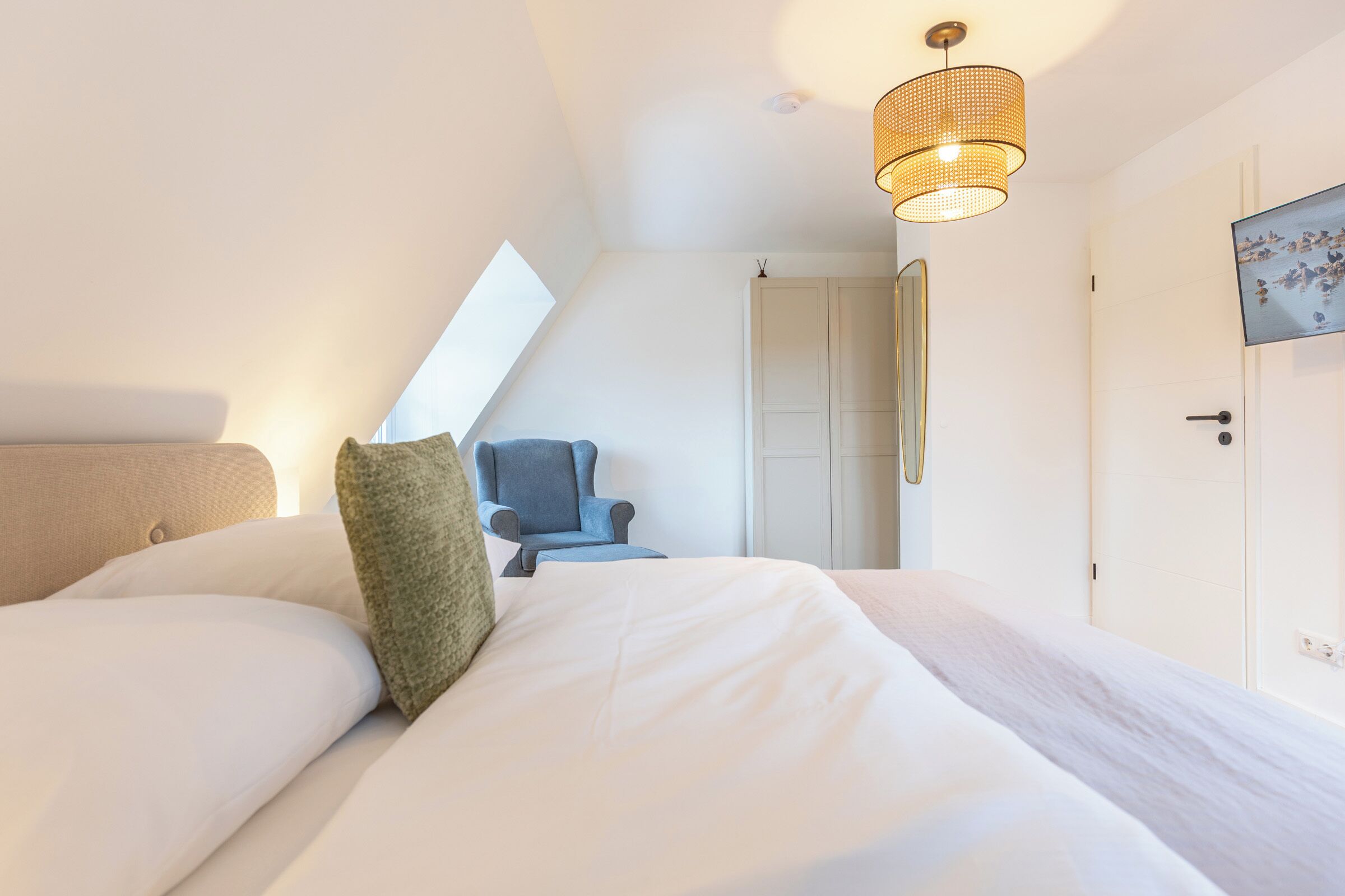 Une chambre à coucher comprenant un lit, une chaise, une armoire et un luminaire fixé au plafond.