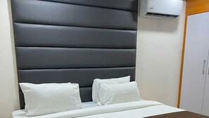 A bed with a dark headboard, white bedding, and a brown throw blanket. - Henods Luxury  Suites (Lagos)