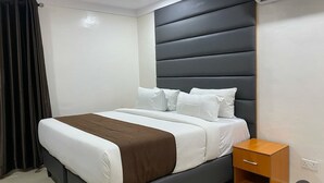 A modern bedroom with a bed, a nightstand, and a dark headboard. - Henods Luxury  Suites (Lagos)