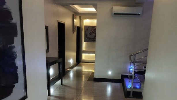 A modern hallway with a tiled floor, recessed lighting, and a staircase with a metal railing. - Henods Luxury  Suites (Lagos)