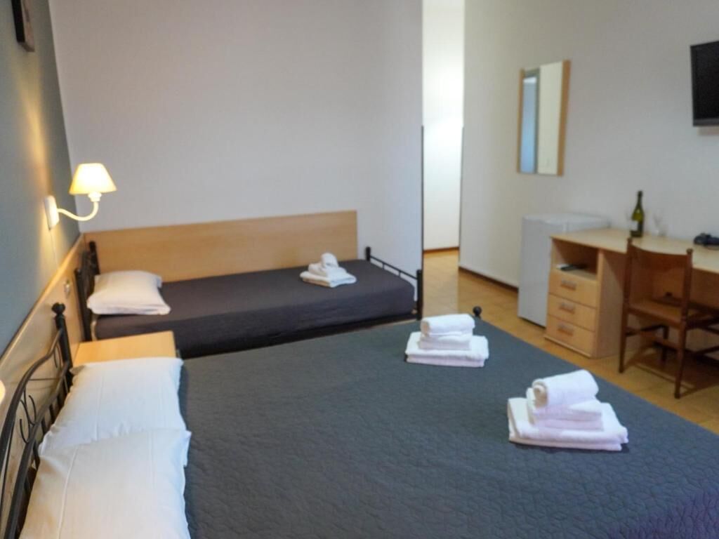 Una habitación de hotel con dos camas individuales, un escritorio, una silla y un televisor.