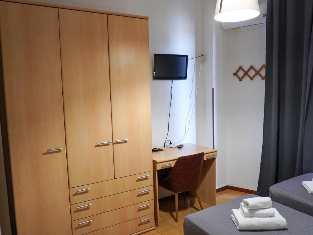 Ein Schlafzimmer mit Bett, Schreibtisch, Stuhl, Kleiderschrank und Fernseher.