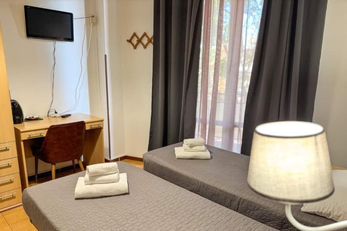 Een hotelkamer met twee bedden, een bureau, een stoel, een televisie en een lamp.
