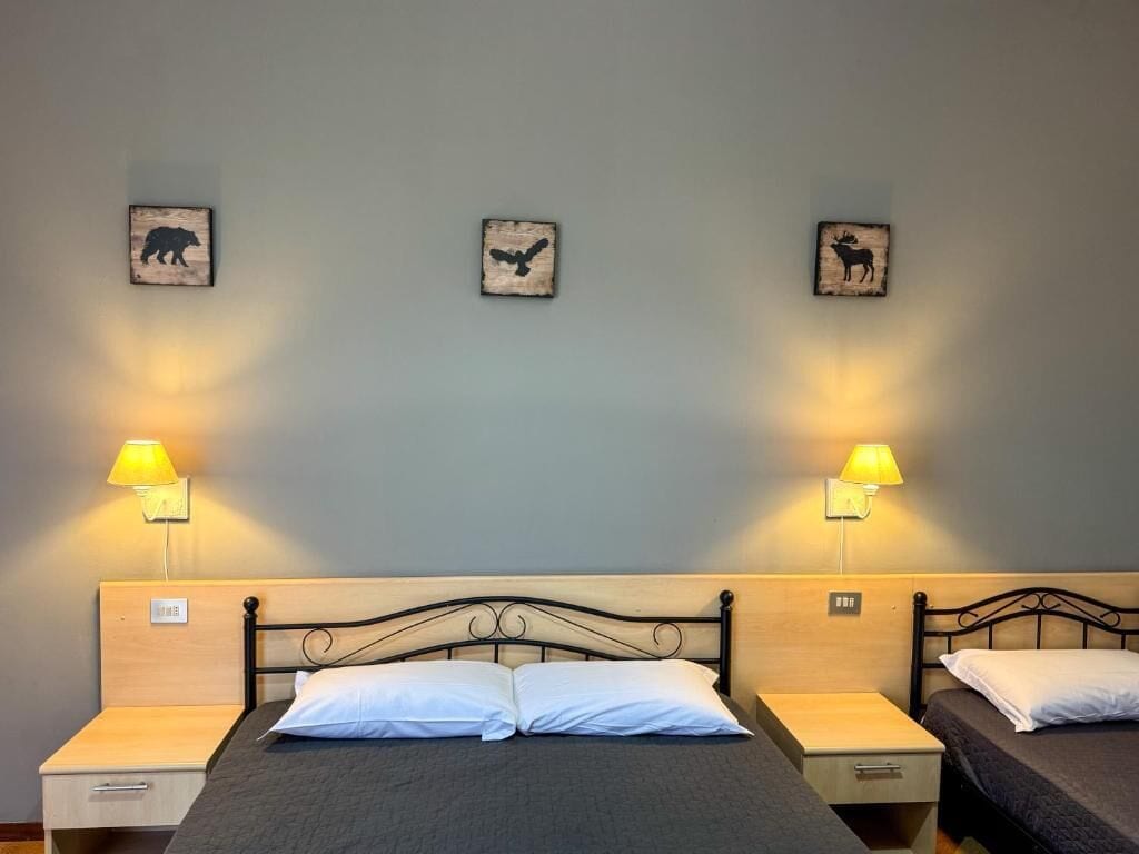 A hotel room with a bed, two bedside tables, two lamps, and three wall-mounted animal-themed decorations.