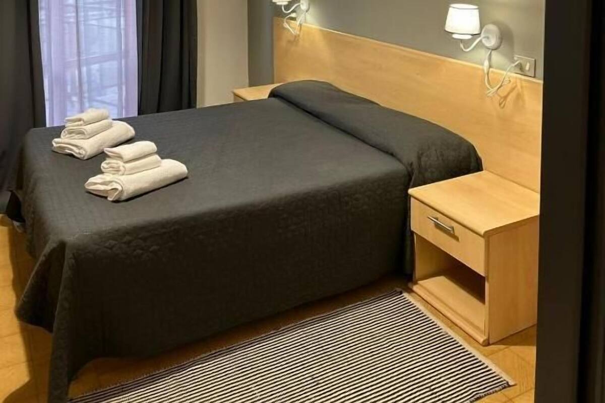 Een moderne hotelkamer met een groot bed, nachtkastjes en uitzicht op het omliggende landschap.