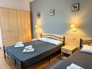 A double bed with a grey bedspread, two bedside tables with lamps, a wardrobe, and wall art. - Hotel Amica (Salsomaggiore Terme)