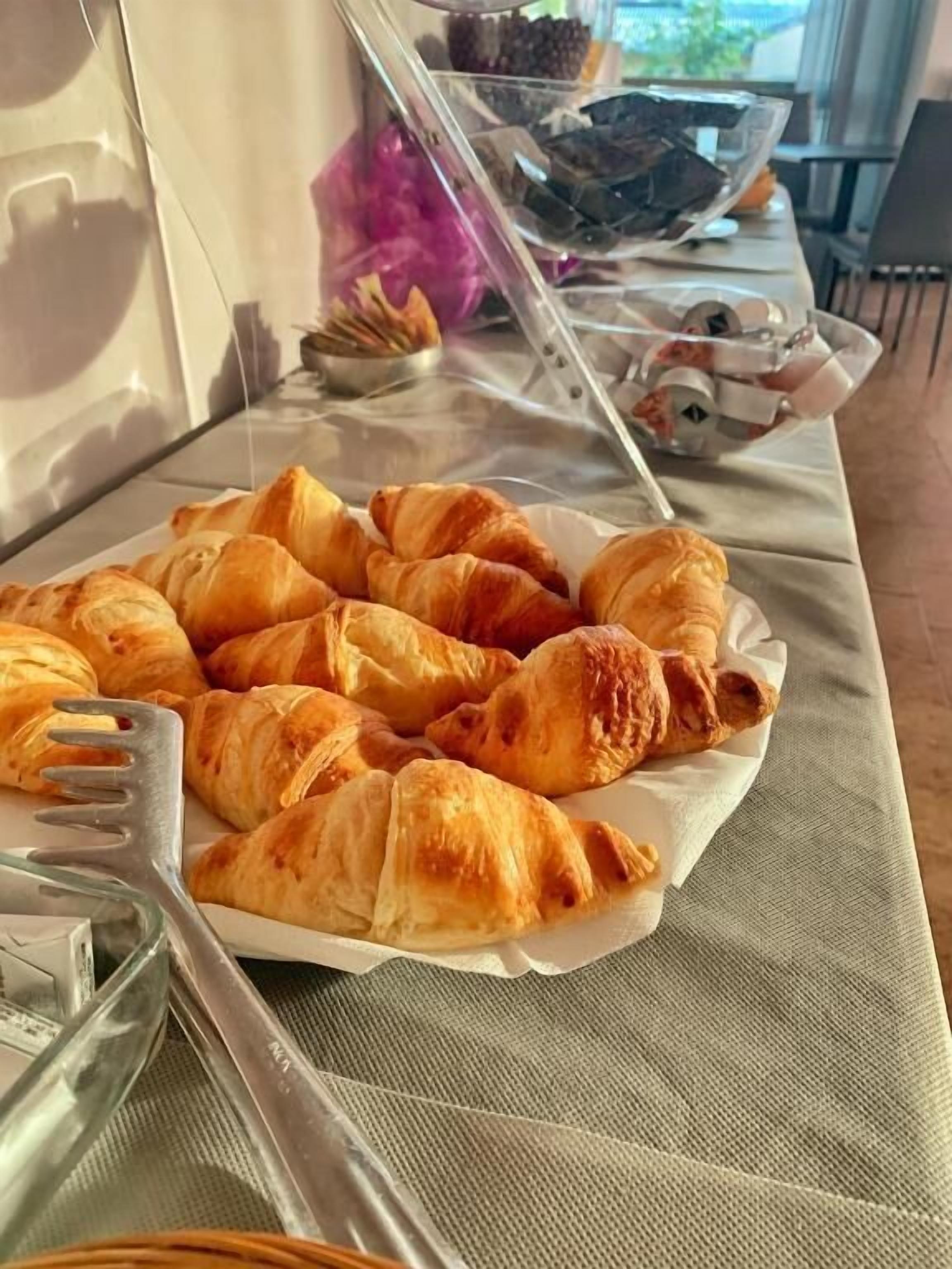 Una mesa con una fuente de cruasanes y un tenedor.