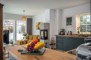 A modern kitchen with a wooden island, a built-in stove, and a large window.