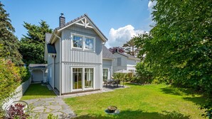 A two-story house with a large front yard, a stone pathway, and a dining area. - Modern living close to the beach for up to 6 people (Dierhagen)