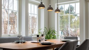 A dining table set with plates, glasses, and cutlery, with a plant and a window in the background. - Modern living close to the beach for up to 6 people (Dierhagen)
