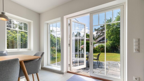 A modern interior with a dining area, large sliding glass doors leading to a patio, and a view of a garden. - Modern living close to the beach for up to 6 people (Dierhagen)