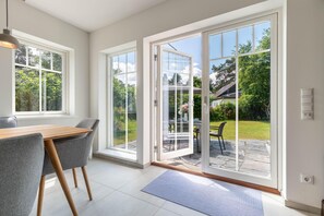 A modern interior with a dining area, large sliding glass doors leading to a patio, and a view of a garden. - Modern living close to the beach for up to 6 people (Dierhagen)