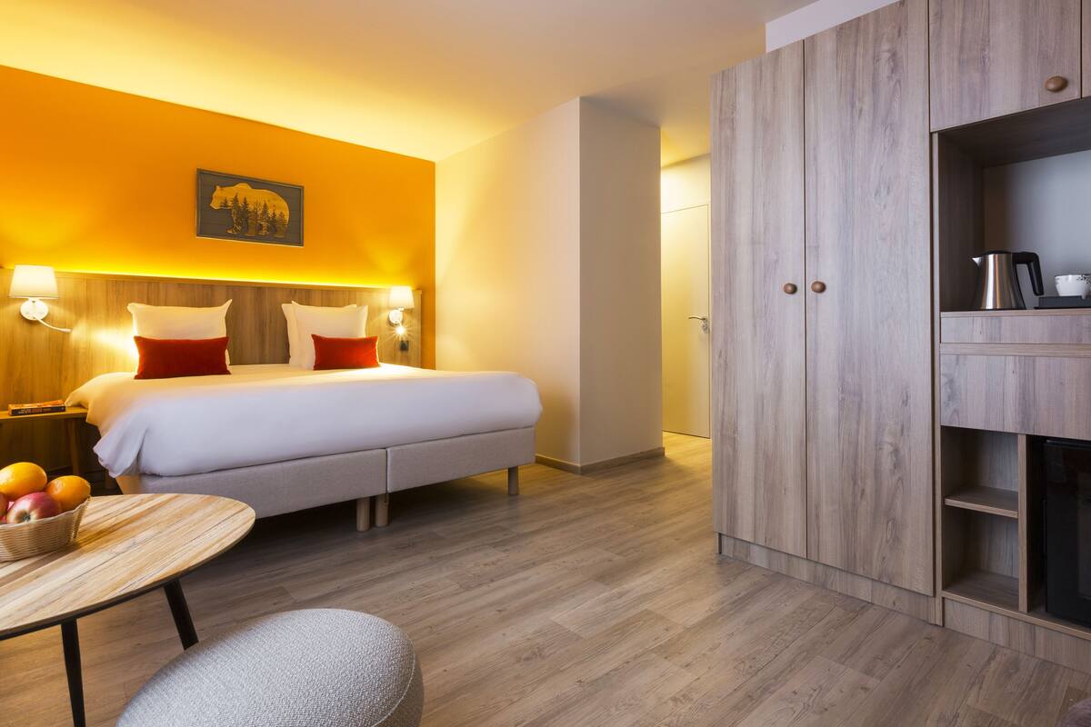 A hotel room with a bed, bedside tables, a desk, and a wardrobe.
