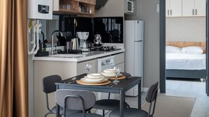 Eine moderne Küche mit Essbereich, inklusive Tisch und Stühlen, einer Kaffeemaschine und einem Kühlschrank.