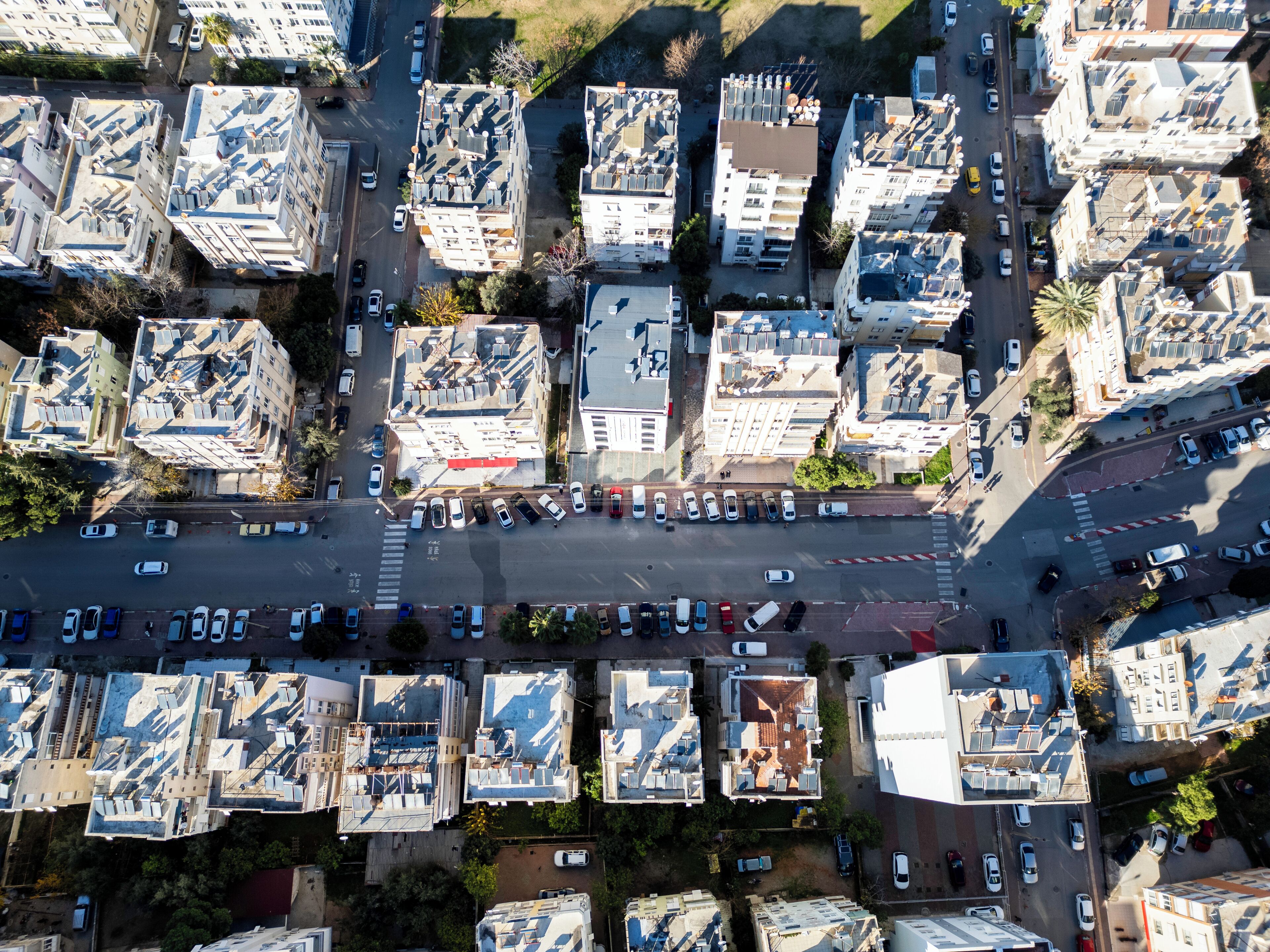 Vista aérea de una zona urbana densamente poblada con rascacielos, una vía principal y automóviles estacionados.