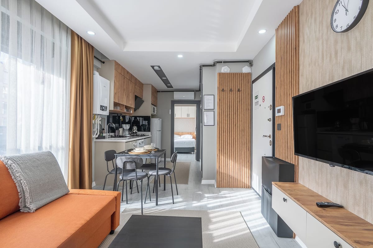A modern living room with a sofa, TV, and dining area.