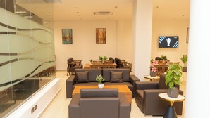 A modern living room with a sofa set, a coffee table, and a TV mounted on the wall. - City Crown Hotel (Dar es Salaam)