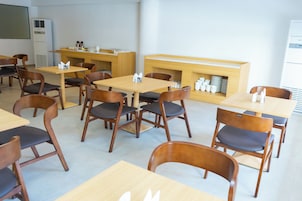 Un comedor con mesas y sillas de madera, una encimera con utensilios de cocina y un aire acondicionado instalado en la pared.