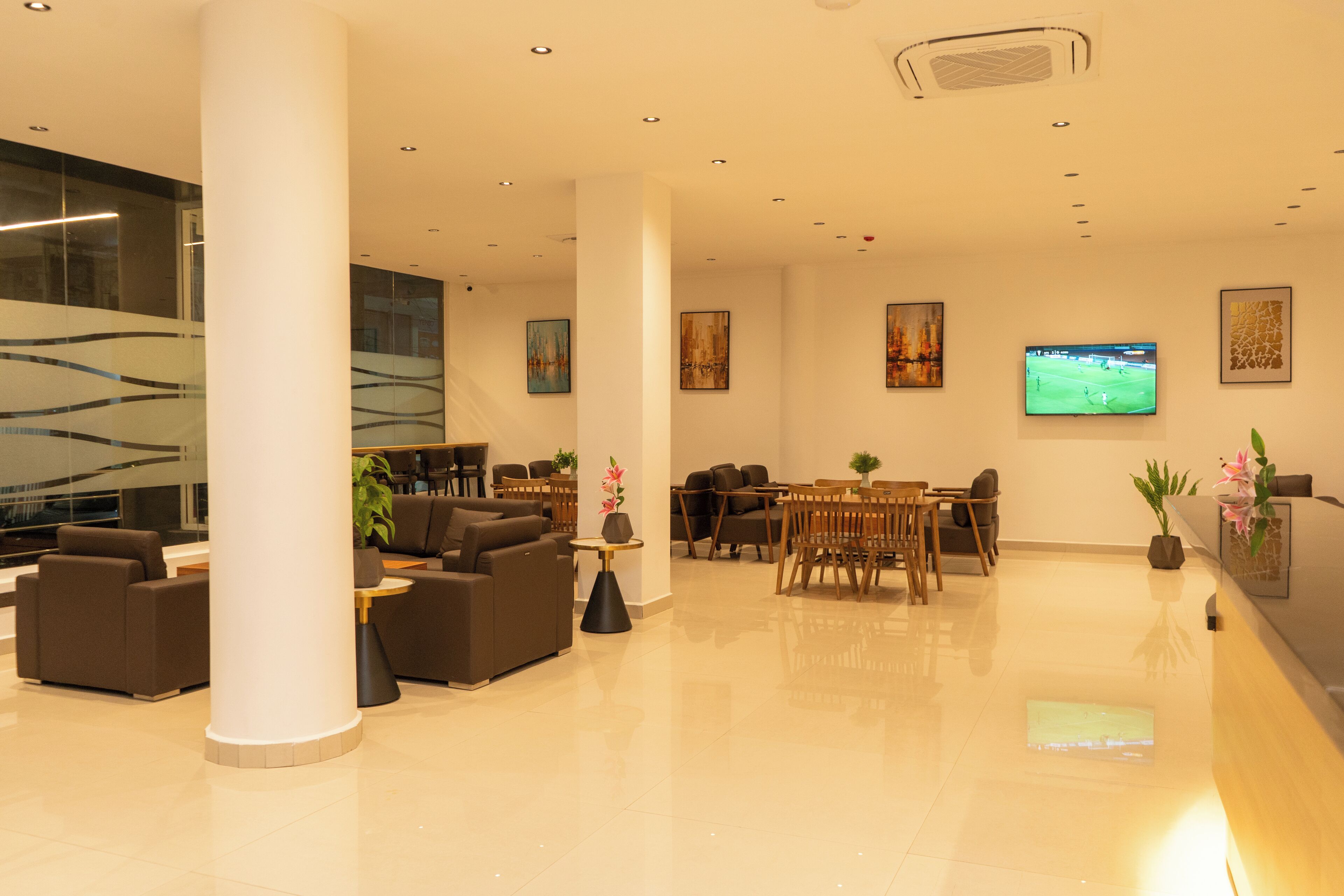 A modern lobby with a seating area, a TV screen, and artwork on the walls.